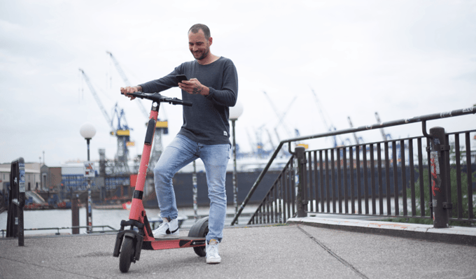 Mann auf Sharing E-Scooter mit Straßenzulassung