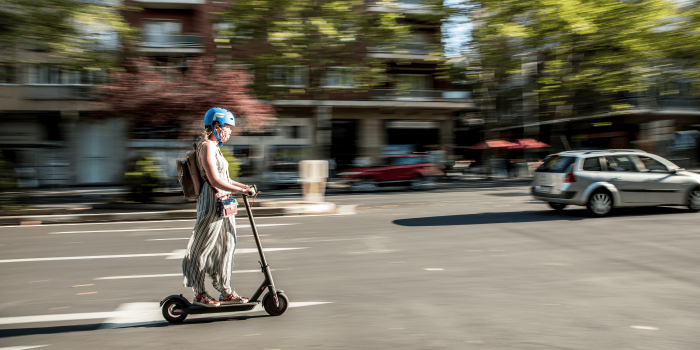 Frau fährt auf E-Scooter mit Straßenzulassung im Stadtverkehr